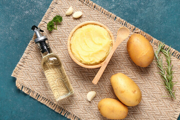 Wooden bowl of tasty mashed potatoes with garlic and rosemary on blue background