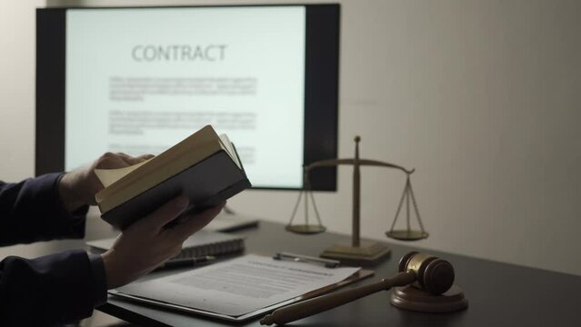 Asian male lawyer working in office at home with law book reading, working with hammer and scales, legal advisor concept