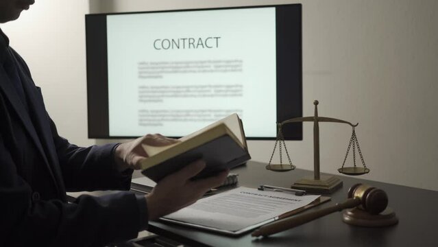 Asian male lawyer working in office at home with law book reading, working with hammer and scales, legal advisor concept