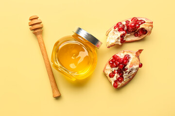 Jar of honey and pomegranate for Rosh Hashanah celebration (Jewish New Year) on yellow background