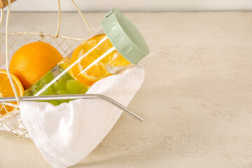 Sports bottle of infused water with grapes and orange on white background