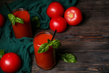 Glasses of tasty tomato juice on black wooden background
