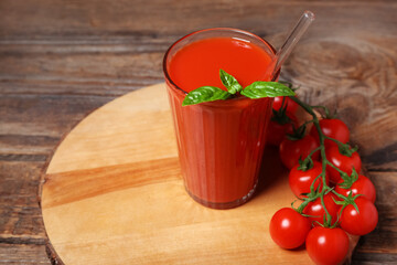 Glass of tasty tomato juice on wooden background