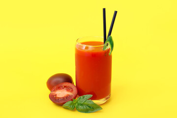 Glass of tasty tomato juice on yellow background