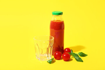 Empty glass and bottle of tasty tomato juice on yellow background