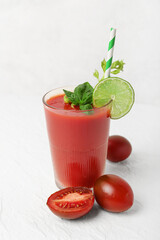 Glass of tasty tomato juice on white background