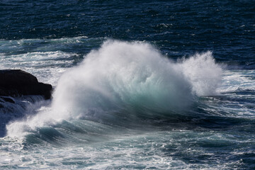 Fototapeta premium Large wave breaking onto rocky sea shore