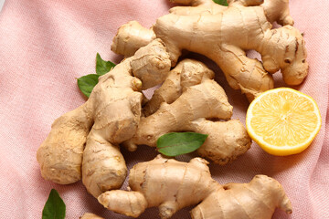 Fresh ginger roots with half of lemon and leaves on napkin, closeup