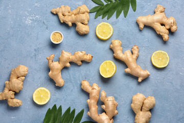 Fresh ginger roots with slices of lemon and leaves on blue background