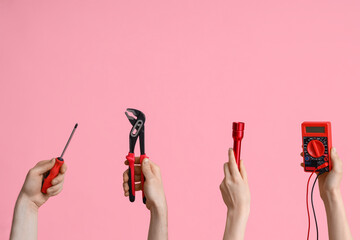 Electrician hands with tools on pink background