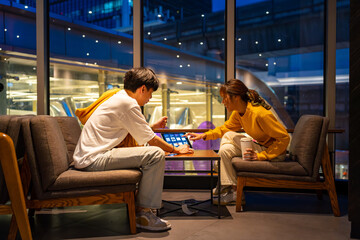 Asian man and woman freelancer working corporate business freelance work job on digital tablet together in cafe at night. Digital nomad people working from anywhere on gadget device online network. - obrazy, fototapety, plakaty