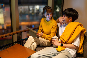 Asian man and woman freelancer working corporate business freelance work job on digital tablet together in cafe at night. Digital nomad people working from anywhere on gadget device online network.