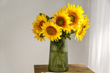 Vase with beautiful sunflowers on table in room, closeup