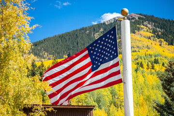 A large American flag waves against a beautiful Colorado fall background.  