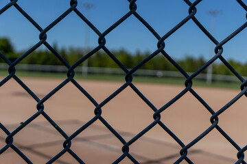 Naklejka premium Wire metal fence with baseball field diamond in background. Taken in Toronto, Canada.