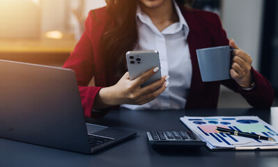 Asian Business woman using calculator and laptop for doing math finance on an office desk, tax, report, accounting, statistics, and analytical research concept