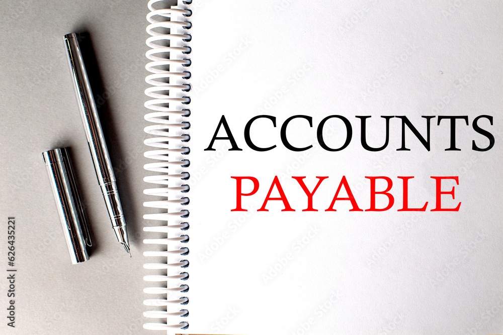 Aufkleber account payable text on a notebook with pen on grey background