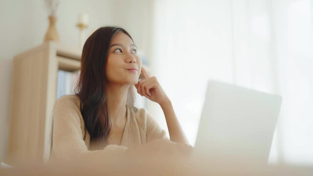 Young asian woman working on computer laptop on desk in living room at home
