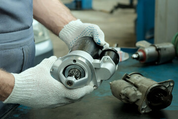 New auto parts. The starter is new in the hands, and the old one is faulty and lies on the desktop....