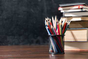 Back to school background with books on wooden table over chalkboard