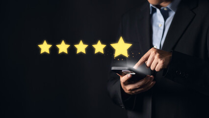 Businessman pointing to a phone with a five stars icon, symbolizing positive customer reviews and...