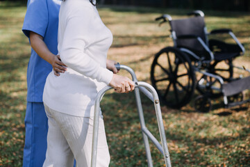 young asian physical therapist working with senior woman on walking with a walker