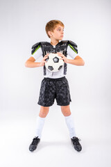 Youth child athletic sports boy holding soccer ball standing in studio wearing soccer football...