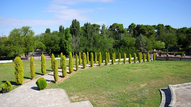 Panning shot of a path with cypresses alongside at Pantheon of the Duchess of Sevillano, Guadalajara, Spain