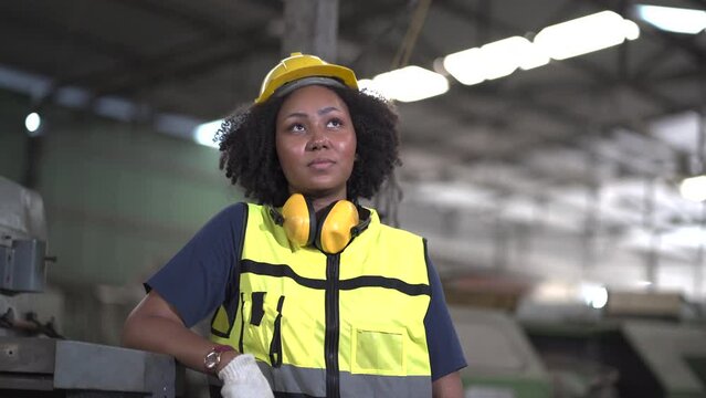 tired African American mechanical engineer worried standing by old machine in factory. black labor worker woman bored work in warehouse . female unhappy in workplace looking up