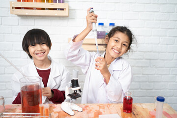 Two cute little girl student child learning research and doing a chemical experiment while making analyzing and mixing liquid in test tube at science class on the table