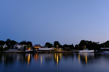 
evening river bank with two ships and houses