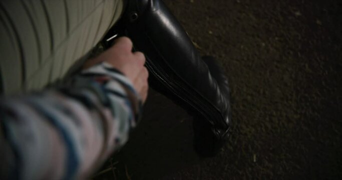 Woman zips up her horse riding boots. Female equestrian rider puts on boots.