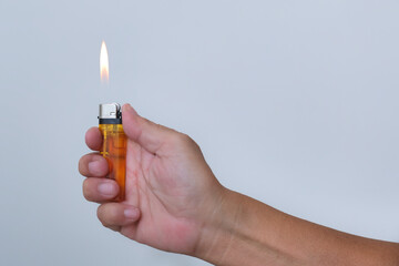 Hand holding a flaming gas lighter over white background