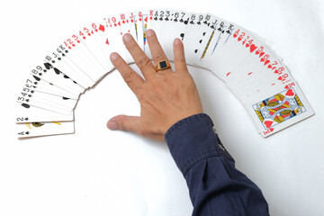 Magician's hand spreading out deck of cards on white table