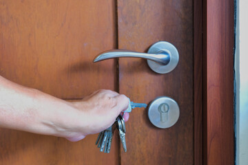 Close-up shot of hand holding keys to open door key hole