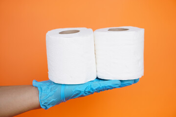 Close up hand holds roll of white tissue paper, isolated on orange background. Concept, cleaning tool, hygienic to wipe dirty and absorb wet ,use tissue paper for hygienic and sanitary.Toilet paper