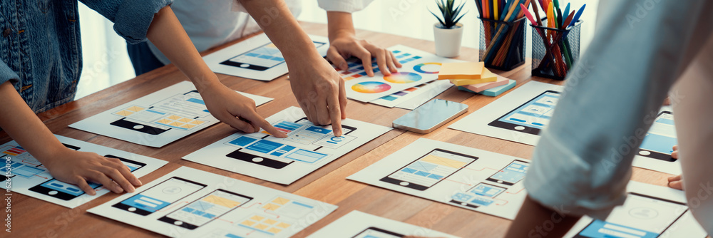 Poster Panorama shot of front-end developer team brainstorming UI and UX designs for mobile app on paper wireframe interface. User interface development team planning for user-friendly UI design. Scrutinize