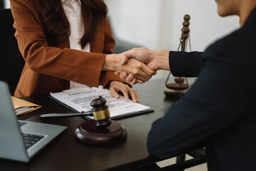 Woman lawyer hand and women client shaking hand collaborate on working agreements with contract documents at the  office. - obrazy, fototapety, plakaty
