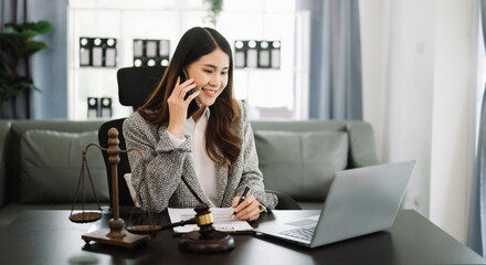 Obraz premium Asian lawyer woman working with a laptop and tablet in a law office. Legal and legal service concept. Looking at camera