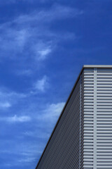 Fototapeta na wymiar Corner of an Industrial Building under blue sky with some clouds