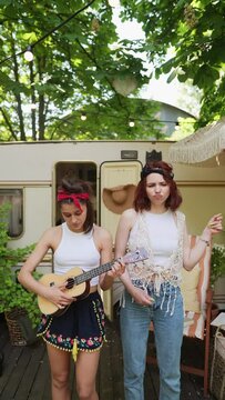 The duo of hippie girls strumming guitars and singing together.