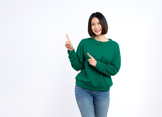 portrait of a Happy Asian woman smiling points her index finger at an empty space in the background and looks straight ahead on white background