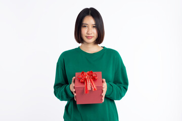 Portrait of a happy pretty asian woman wear green shirt holding red present box and looking at camera isolated on white background
