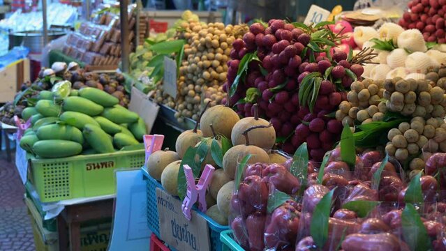 Fruits captured while the camera slides to the left while an unrecognized woman moves to the left, Fruit stand, Thailand