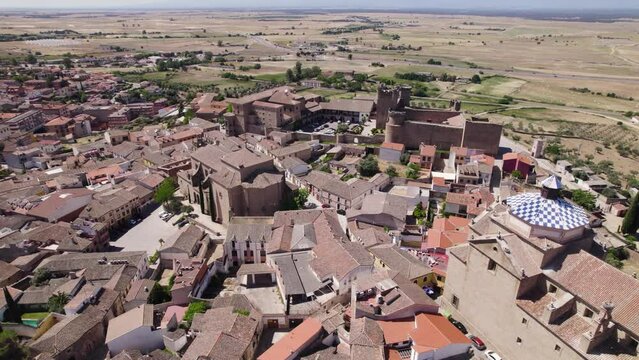 Orbiting aerial view over Oropesa neighbourhood houses and castle against the scenic Spanish countryside mountain landscape