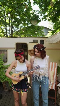 Two hippie girls playing the guitar and singing.