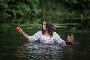 A young beautiful girl swims in the river in a place with pit bull terriers.