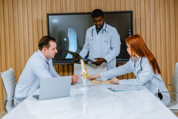 Obraz premium Surgeon and radiologist discuss Pt's ankle's MRI for treatment plan. Multicultural boardroom meeting