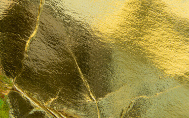 Macro image, golden and rough paper texture. Reflection and uneven background,