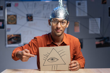 Strange man in a foil hat with masonic symbol All-seeing eye of God. Fake news conspiracy theories